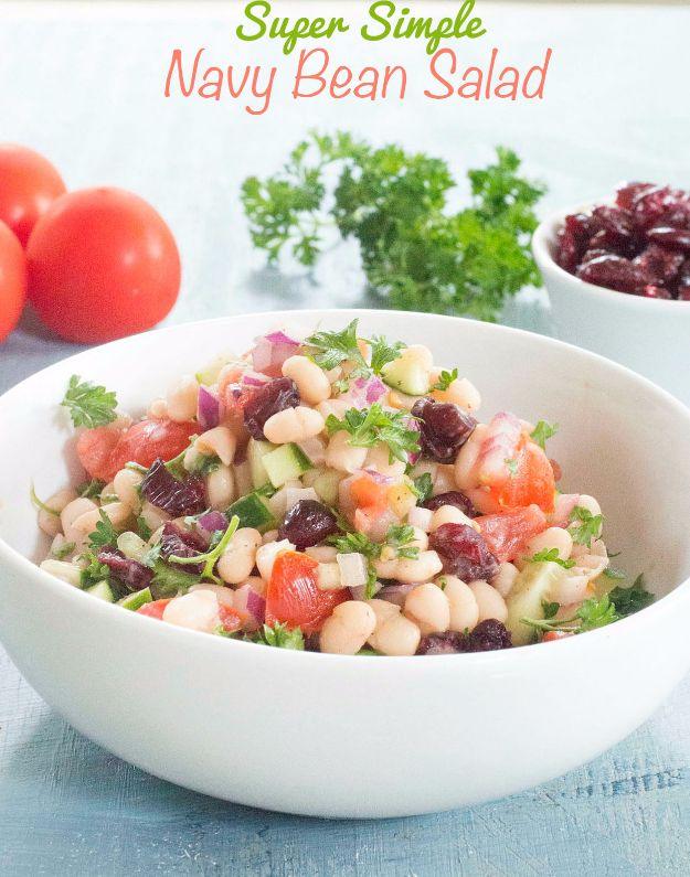 Navy beans salad, white beans with chopped tomato, red onion, parsley and dried cranberries in a white bowl