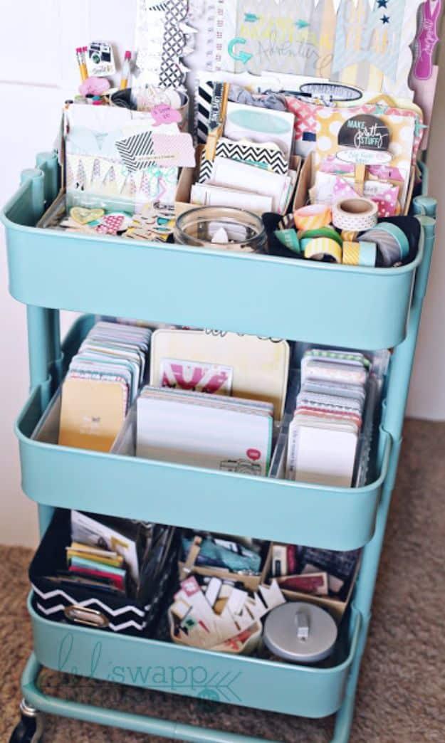 Teal three tier rolling cart packed with card stock, patterned paper, journaling cards, washi rolls and small boxed supplies
