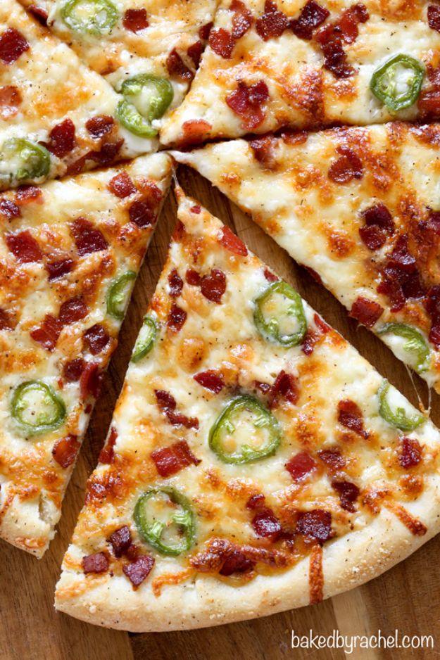 Sliced thin crust jalapeno popper pizza covered in melted cheese, bacon crumbles and green jalapeno rounds