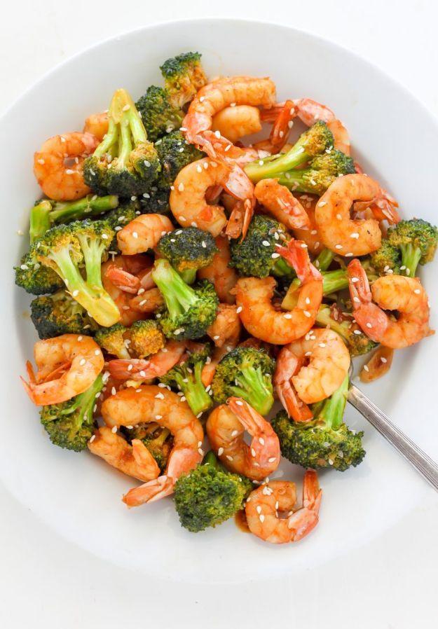 Sriracha shrimp and broccoli on a white plate, pink shrimp and broccoli florets in a glossy sauce with sesame seeds