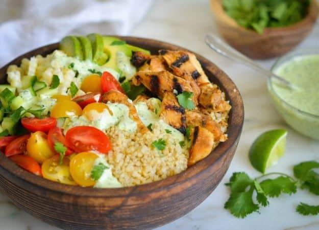Chicken and quinoa burrito bowls with grilled chicken, corn, tomatoes and avocado drizzled in green sauce