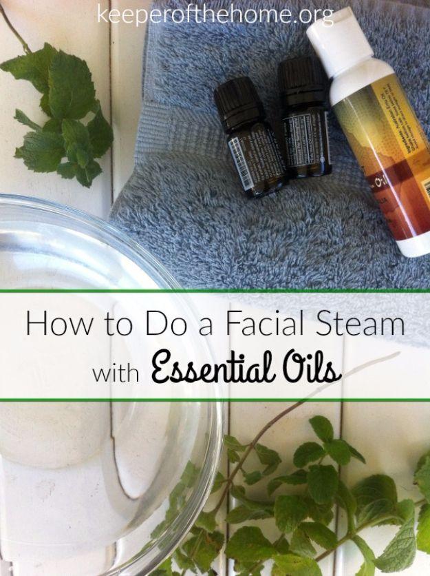 Facial steam with essential oils, a glass bowl of water and fresh herbs beside essential oil bottles on a grey towel