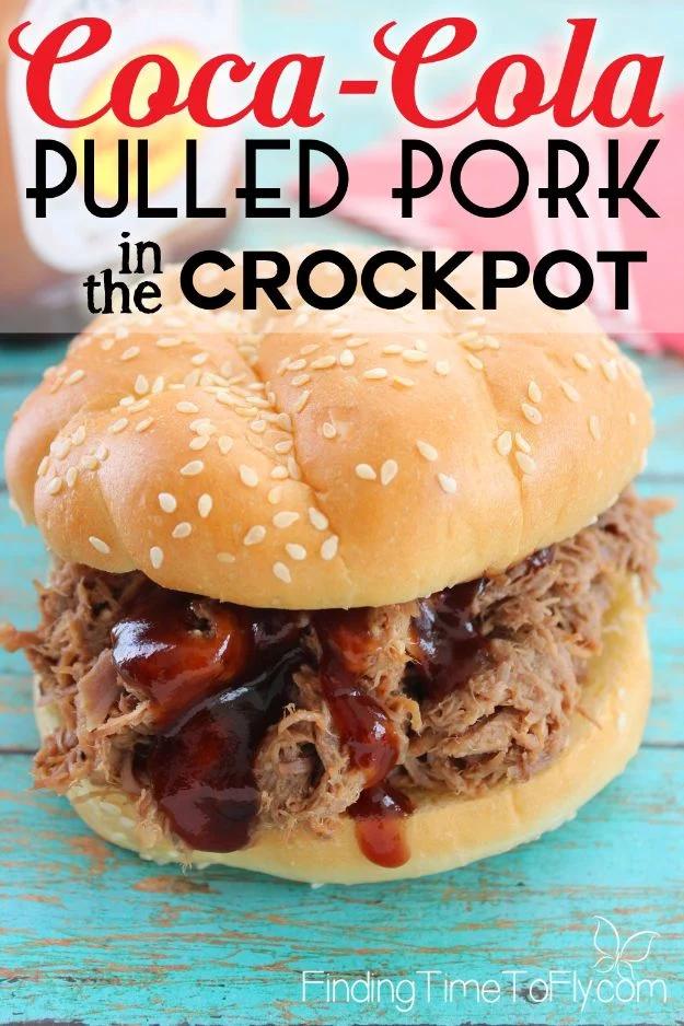 Crockpot Coca-Cola pulled pork piled on a sesame seed bun with barbecue sauce on a turquoise painted table