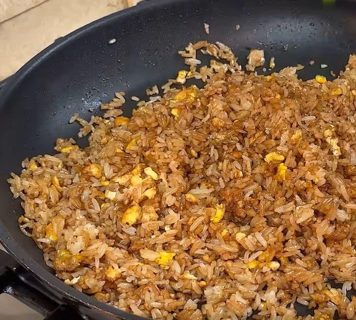 Cooking rice with dark soy sauce and fried eggs in a pan