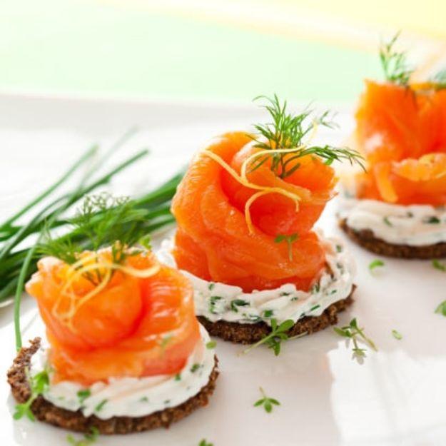 Rye crisp breads topped with herbed cream cheese, twisted smoked salmon roses, dill sprigs and lemon zest