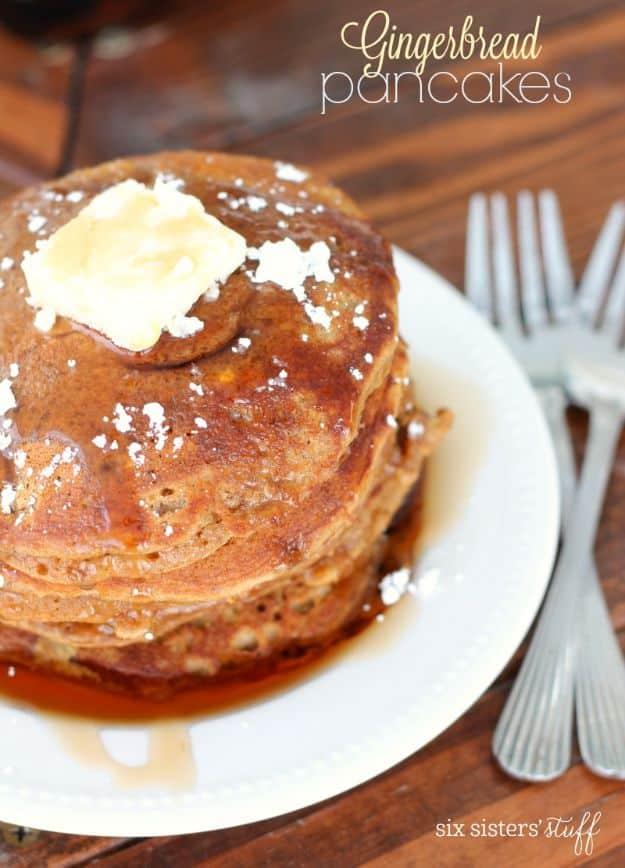 Gingerbread pancakes stacked with a pat of butter, powdered sugar and syrup running down onto the plate