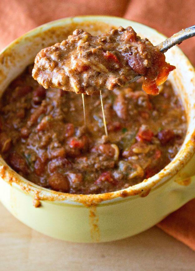 Simple classic beef chili in a pale yellow enamel pot with a metal spoon lifting out a heaped spoonful