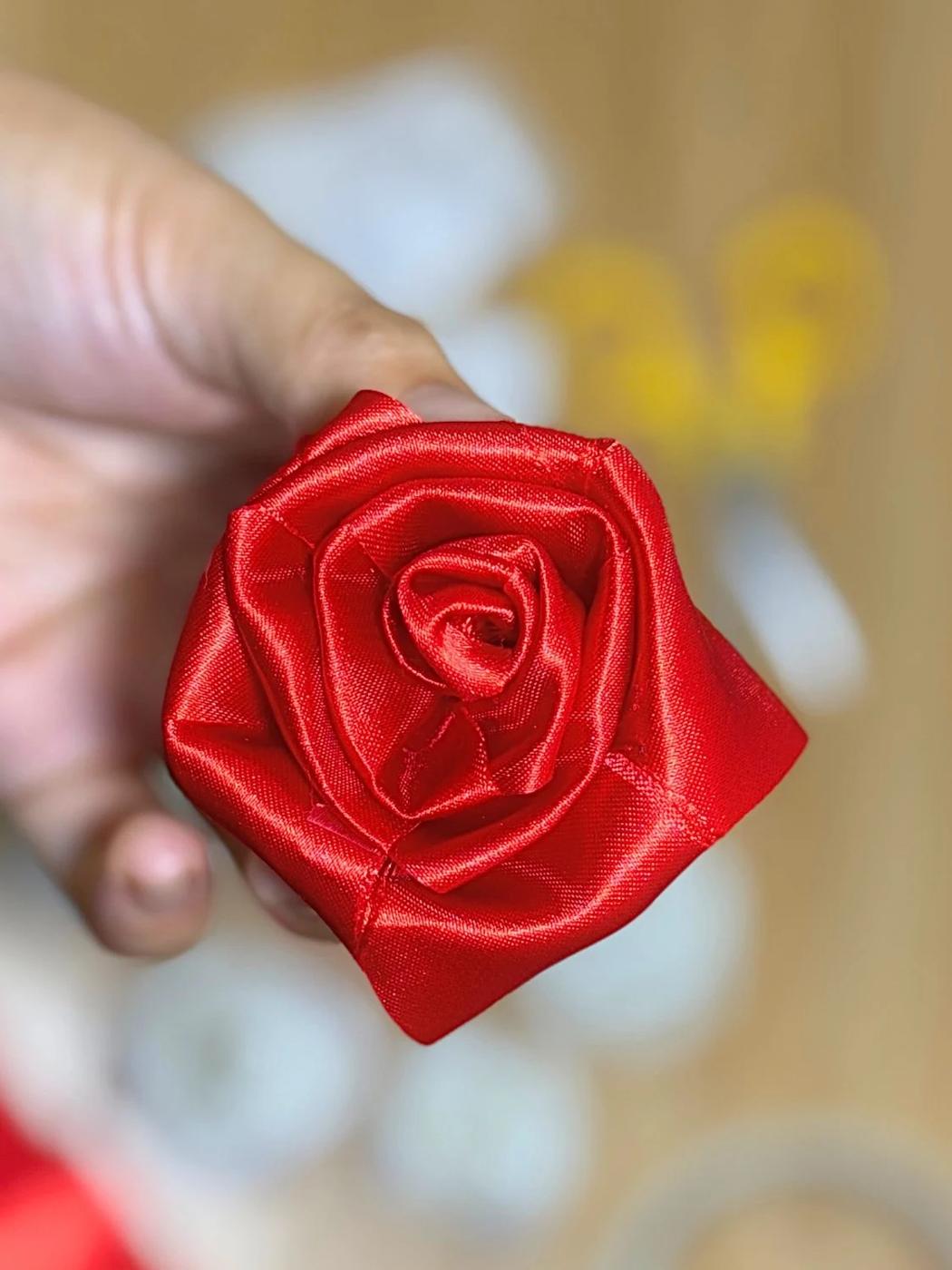 A small rose rolled from a length of ribbon sitting on top of a wrapped gift as a quick elegant topper