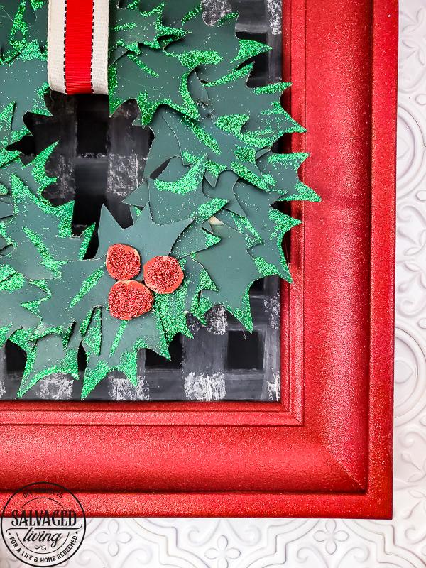 Ornate picture frame spray painted in red glitter with a green glitter holly and red berry cluster in one corner