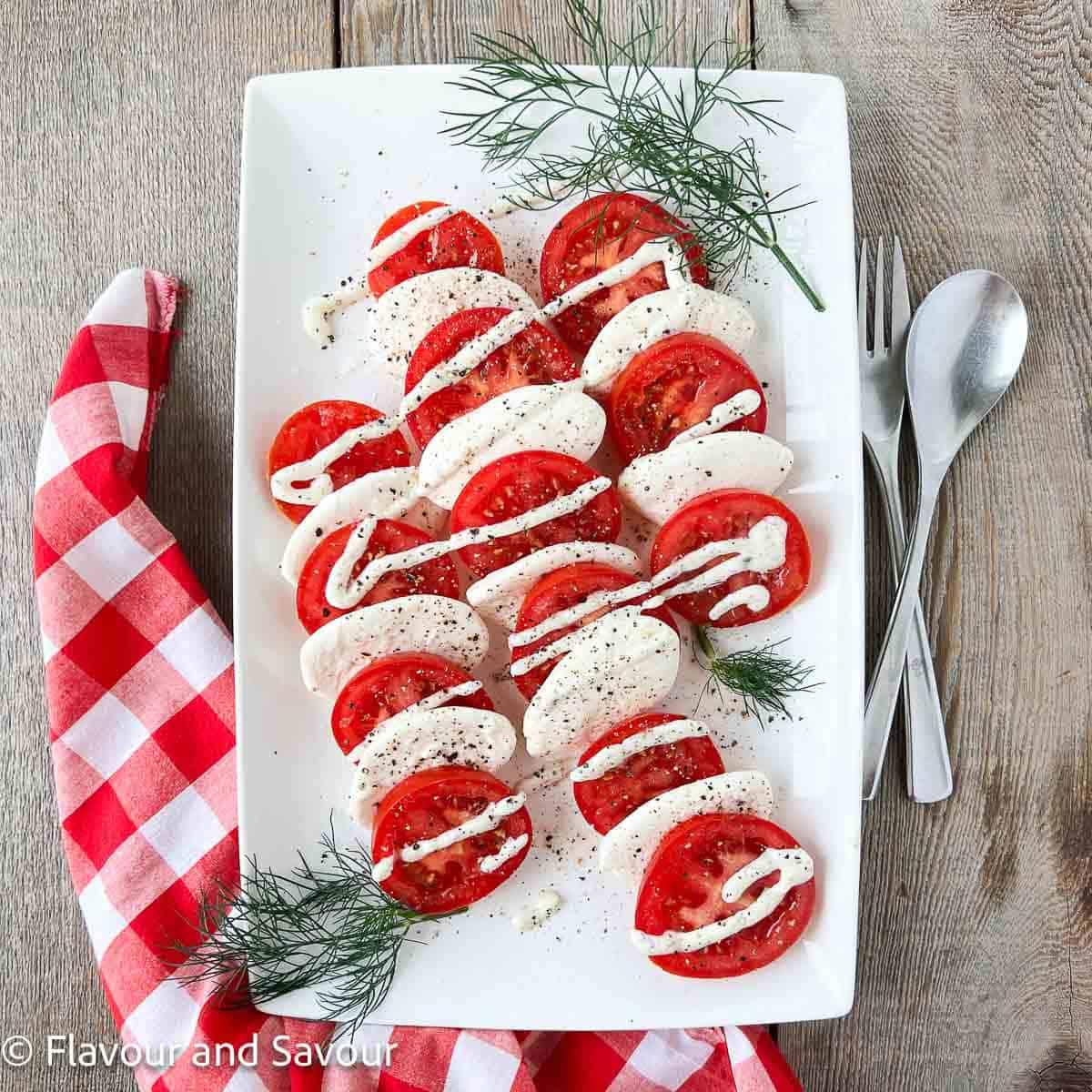 Dill caprese salad with sliced ripe tomatoes, fresh mozzarella medallions and a creamy yogurt dill dressing