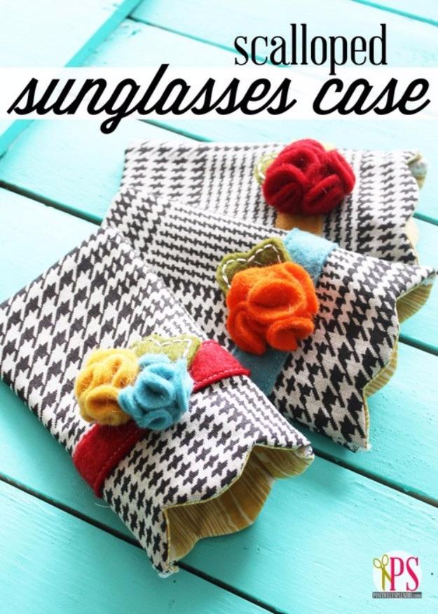 A padded sunglasses case in printed cotton with a scalloped top edge and a small snap closure, resting on a pale cloth