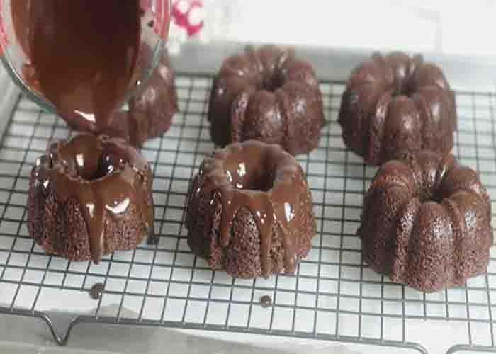 Pouring the chocolate ganache over the mini bundt cakes