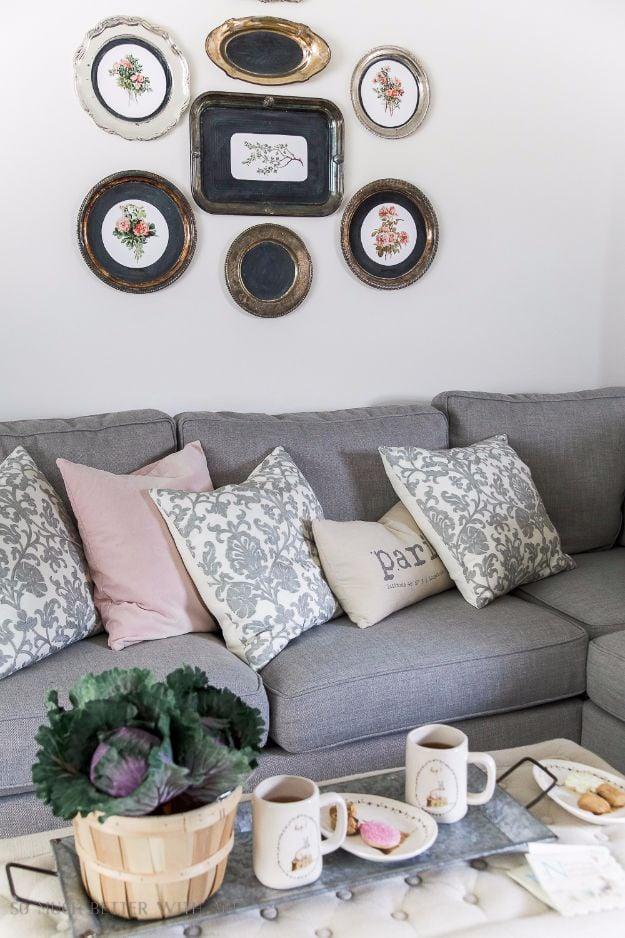 Vintage floral printables mounted in silver platters and trays hung as a gallery wall above a gray sofa