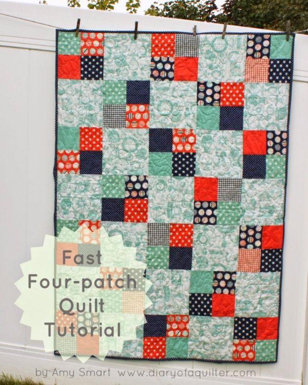 Fast four patch quilt in mint green, navy and red squares hanging on a clothesline against a white fence