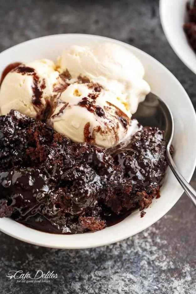 Hot fudge chocolate pudding cake in a white bowl with fudge sauce and two scoops of vanilla ice cream