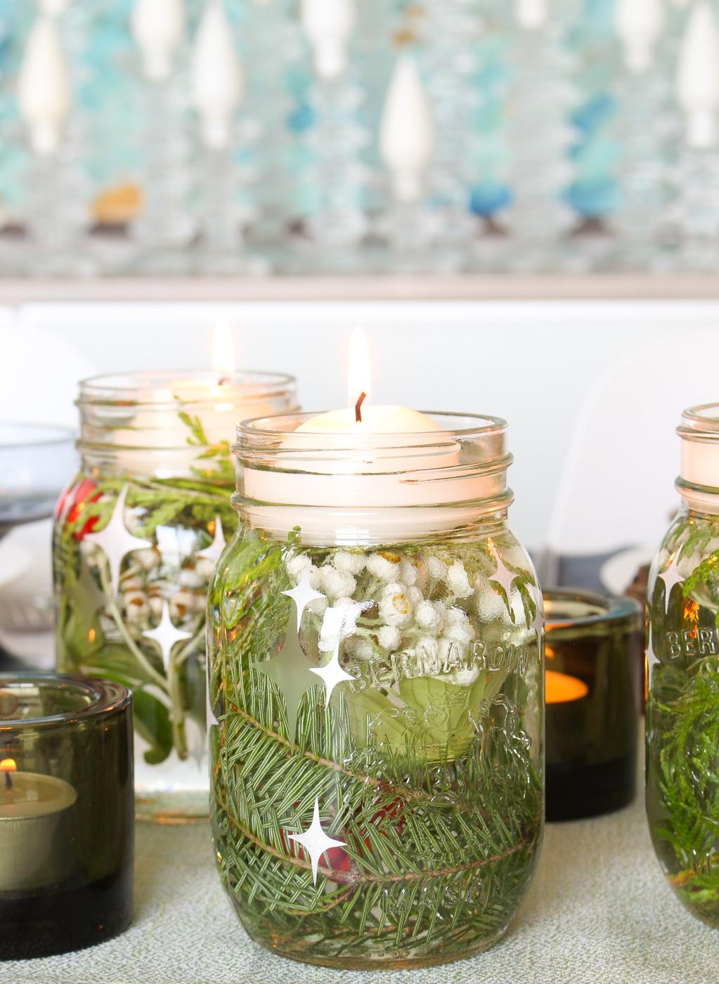 Three glass jars etched with frosted stars and topped with glittery star stickers, each holding water and a floating candle