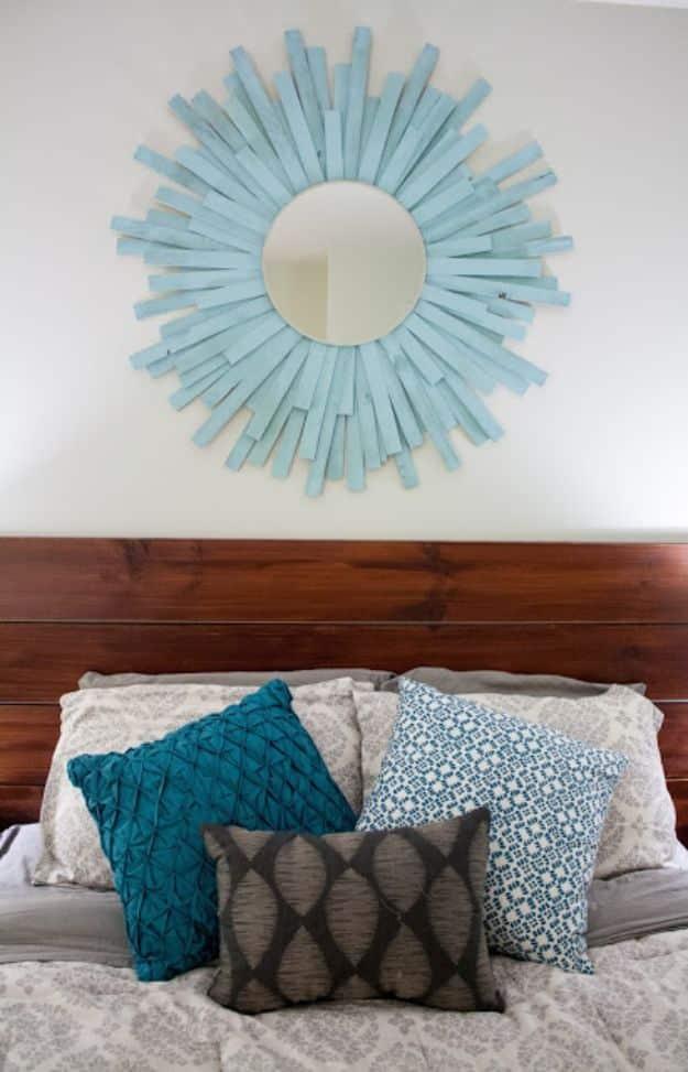 DIY starburst mirror, a pale blue sunburst mirror of fanned wooden shims hanging above a wooden headboard