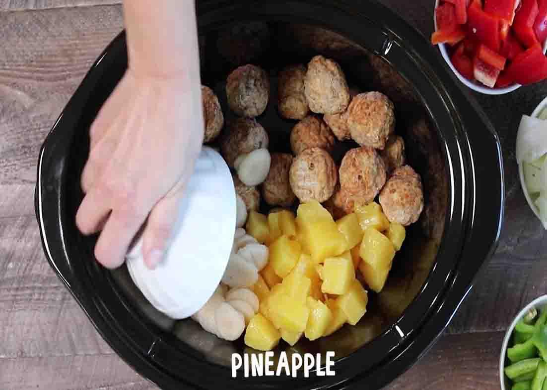 Adding the sweet and sour meatballs ingredients to the slow cooker