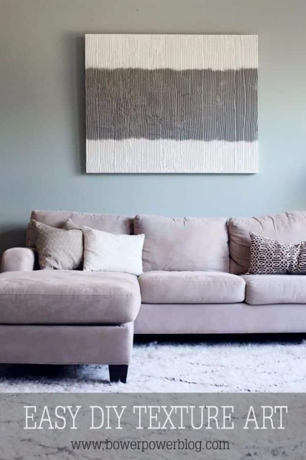 Large textured canvas wall art in white with a wide soft gray horizontal band, hanging above a pale gray sofa