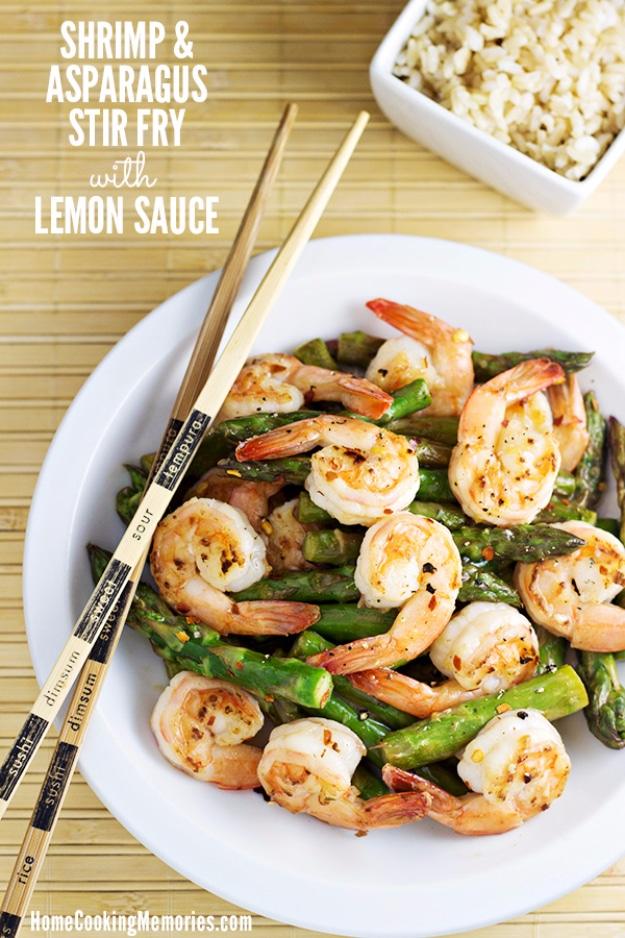 Shrimp and asparagus stir fry in a glossy lemon sauce with garlic and ginger in a large frying pan ready to serve over rice