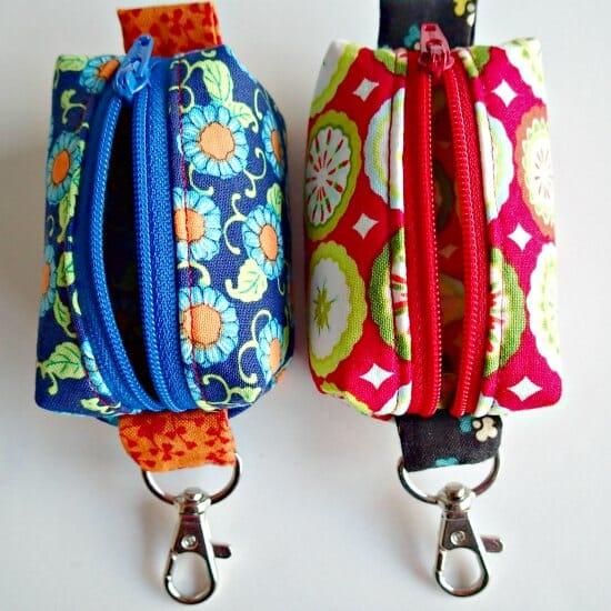 Two teeny tiny zipper pouches in blue floral and red diamond print fabric with swivel clasps on a white background