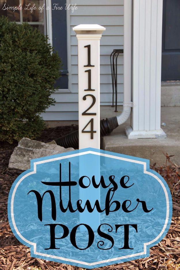 White house number post with a solar light cap and black numbers, standing in a mulched front garden