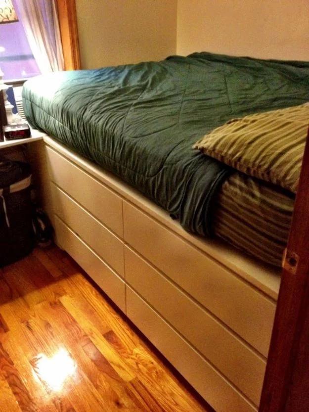 Photograph of a raised bed platform built around a pale birch six drawer dresser with green bedding beside a window
