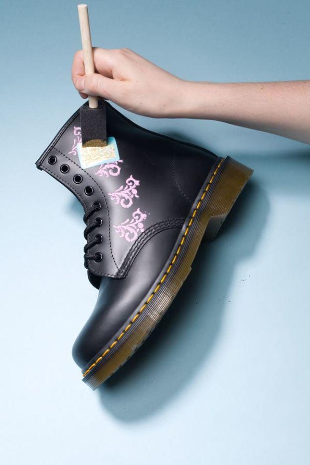 Baroque inspired boots, a black Dr Martens boot being stenciled with pink and gold scrollwork by hand