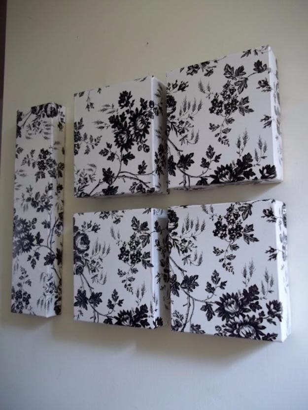 Five cardboard boxes covered in black and white toile contact paper, grouped as wall art on a cream wall