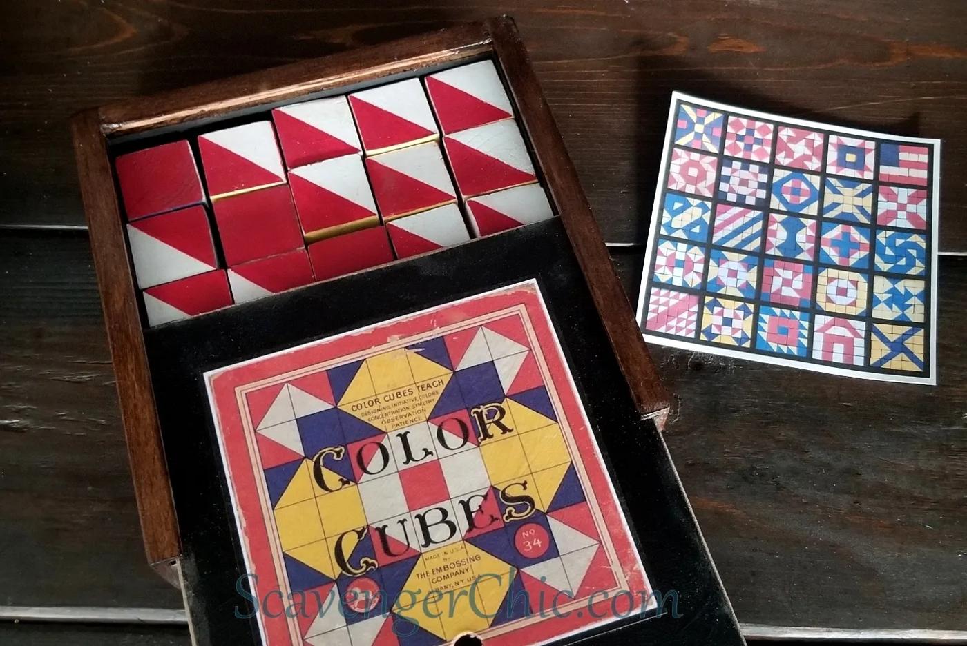 A wooden box of handmade red and white painted color cubes with a vintage label and a printed card of quilt block patterns