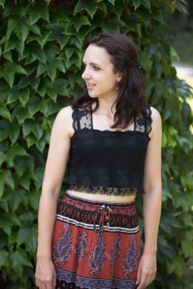Laced crop top, a woman in a black lace cropped tank top and patterned drawstring shorts in front of a wall of ivy