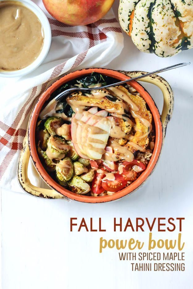 Fall harvest power bowl with roasted squash rings, brussels sprouts and kale beside a bowl of tahini dressing