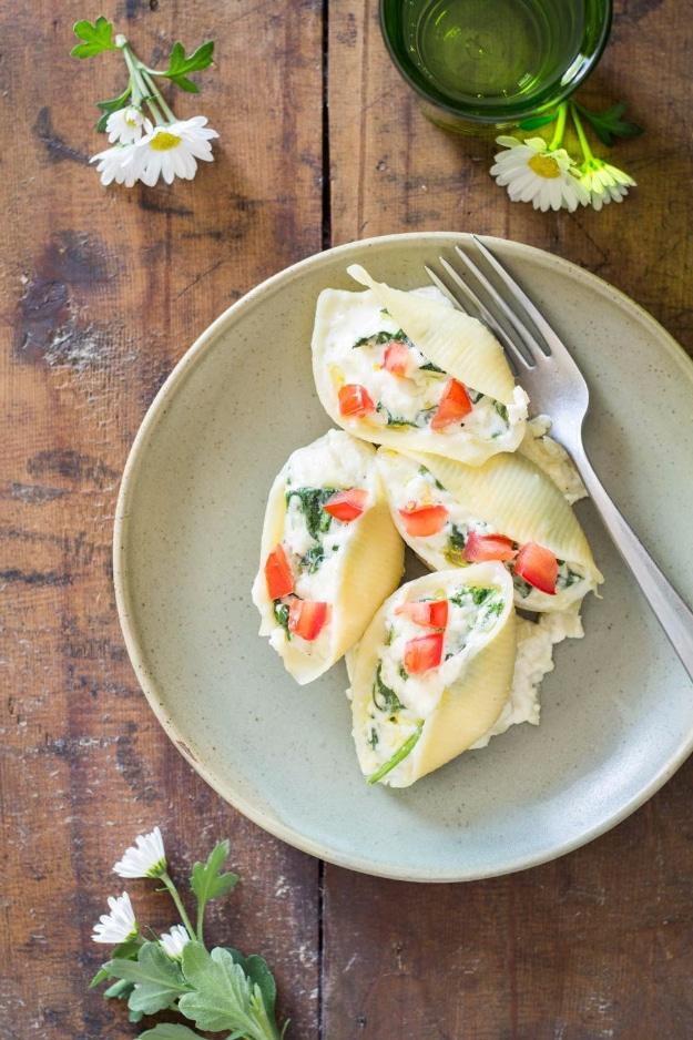 Spinach and ricotta stuffed pasta shells baked in tomato sauce under melted cheese in a white dish ready to serve at home