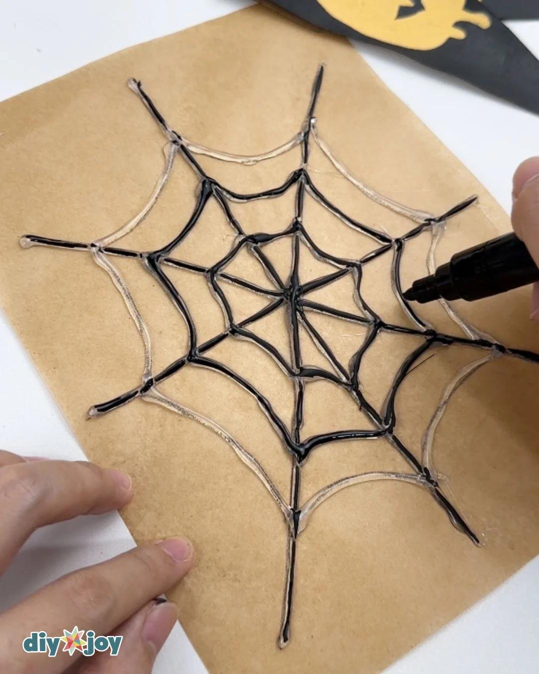 Easy Halloween Decorations - an acrylic marker coloring the set hot glue web black while the outer strands are still clear