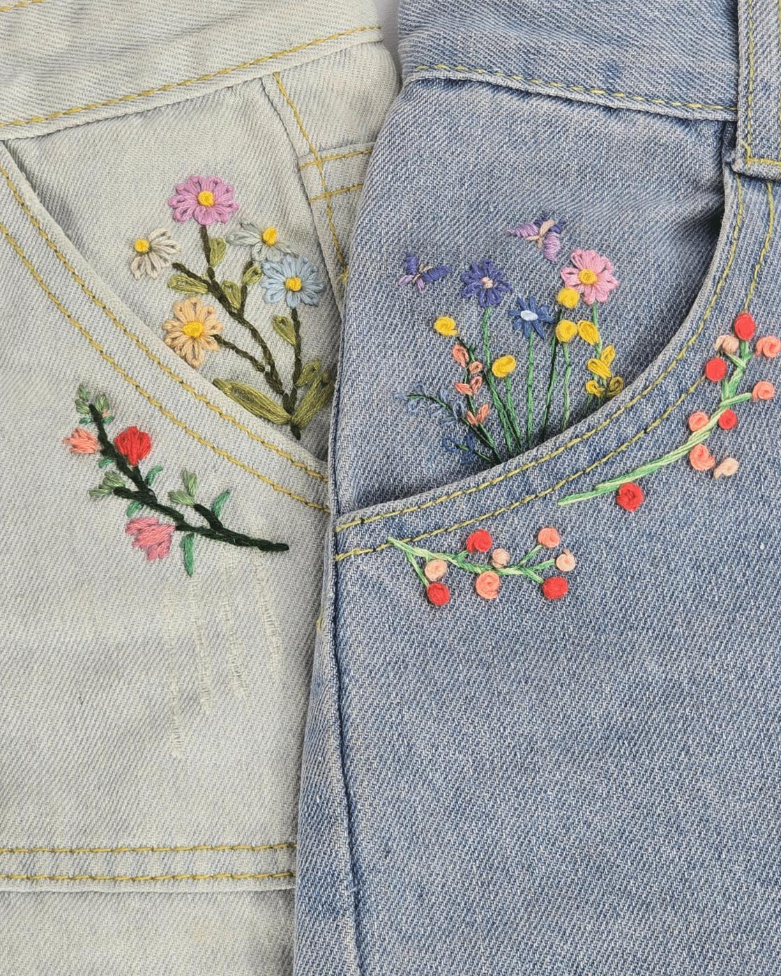 Hand stitched floral embroidery on denim jeans, finished flowers worked in bright colored cotton floss