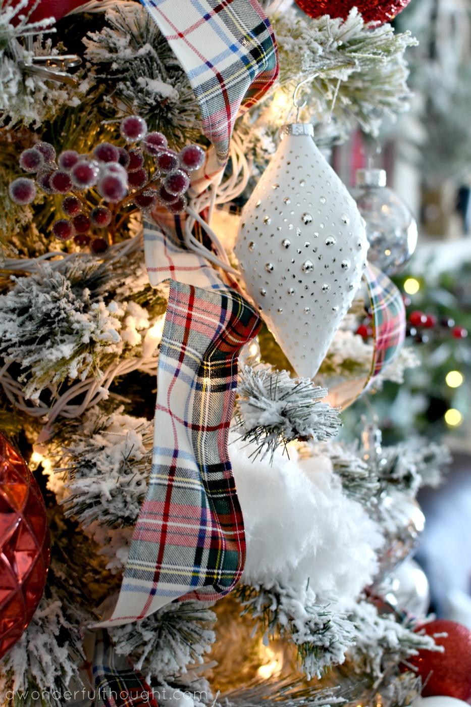 Homemade plaid wired ribbon threaded through a flocked Christmas tree with white and silver ornaments