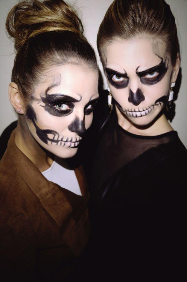 Glam skeleton Halloween makeup on two women with black eye sockets, white base and painted teeth on the lips