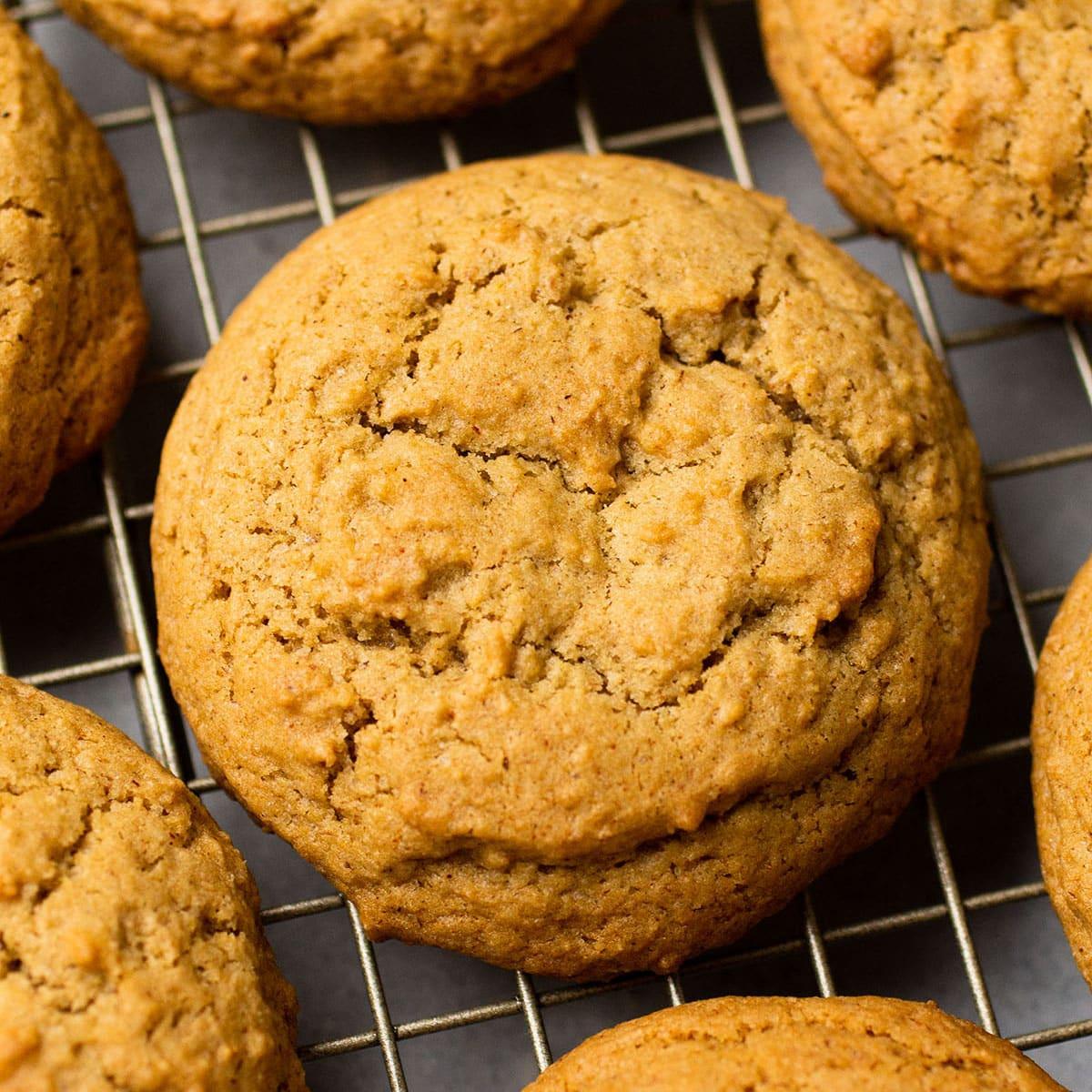Puffy golden cinnamon brown sugar cookies with crackled tops cooling on a wire rack, one large cookie in the center