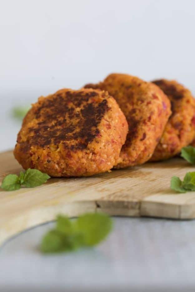 Fried chicken and bacon patties, three golden browned patties stacked on a wooden board with fresh basil