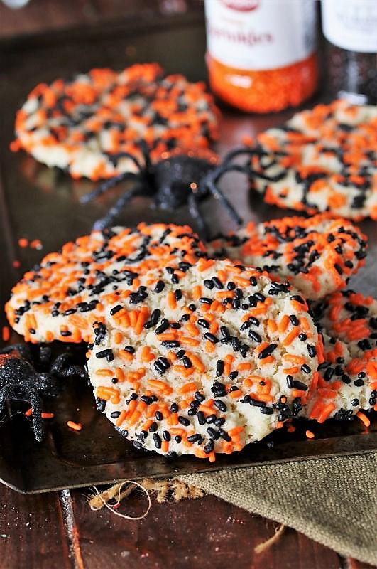 Soft sugar cookies rolled in orange, black, purple and green Halloween sprinkles before baking on a tray