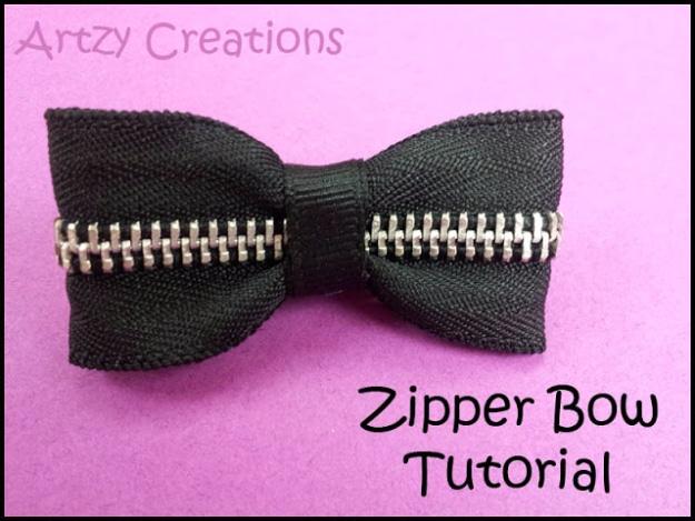 Black zipper bow with silver teeth and a tape wrapped centre band resting on a bright pink felt background