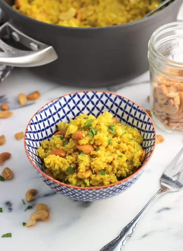 Coconut turmeric quinoa with cashews, golden yellow from turmeric and scattered with cashew pieces in a bowl