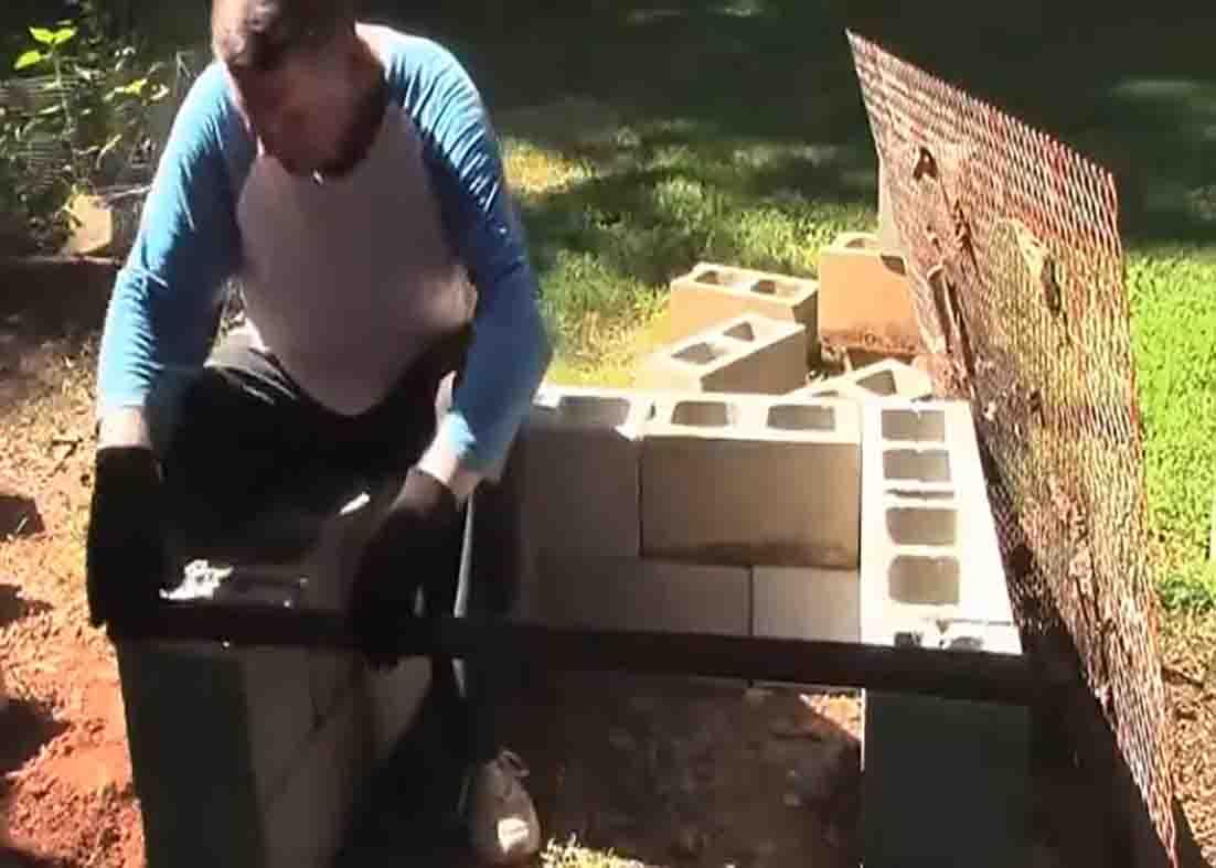Cinder blocks stacked and leveled for a DIY backyard grill with the angle iron set across the two half blocks