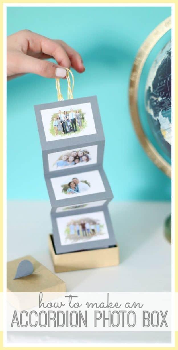 A hand lifting a strip of four framed photos out of a small gold box, turquoise backdrop with a globe behind