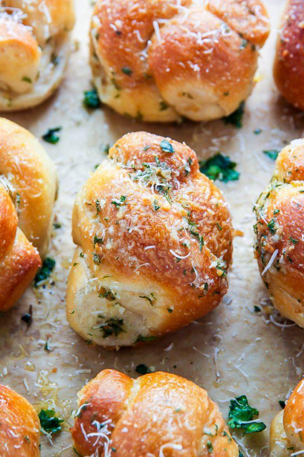Homemade garlic knots brushed with parsley butter and grated parmesan with a bowl of marinara for dipping
