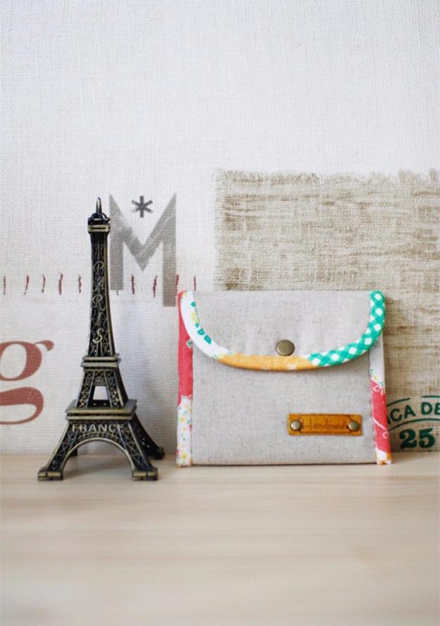 Small oatmeal linen flap coin purse with a floral bound edge, a brass snap and a stamped leather tab on front