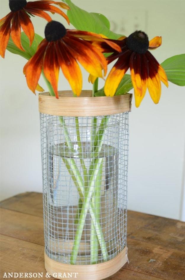 Hardware cloth vase, a glass vase wrapped in wire mesh with wood bands top and bottom holding black eyed Susans
