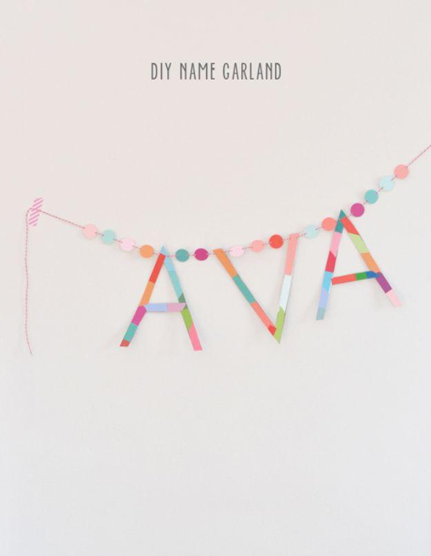 DIY baby shower decoration name garland spelling AVA in multicolored paper strips between punched paper dot strings