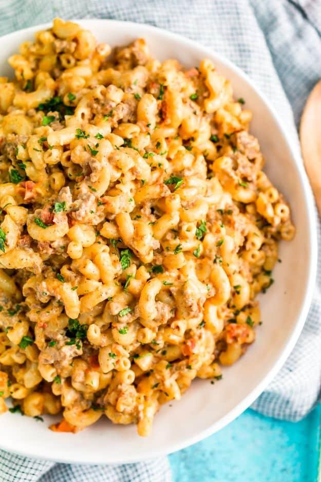 One pot chili mac and cheese in a white bowl with ground beef and tomatoes through the macaroni and parsley