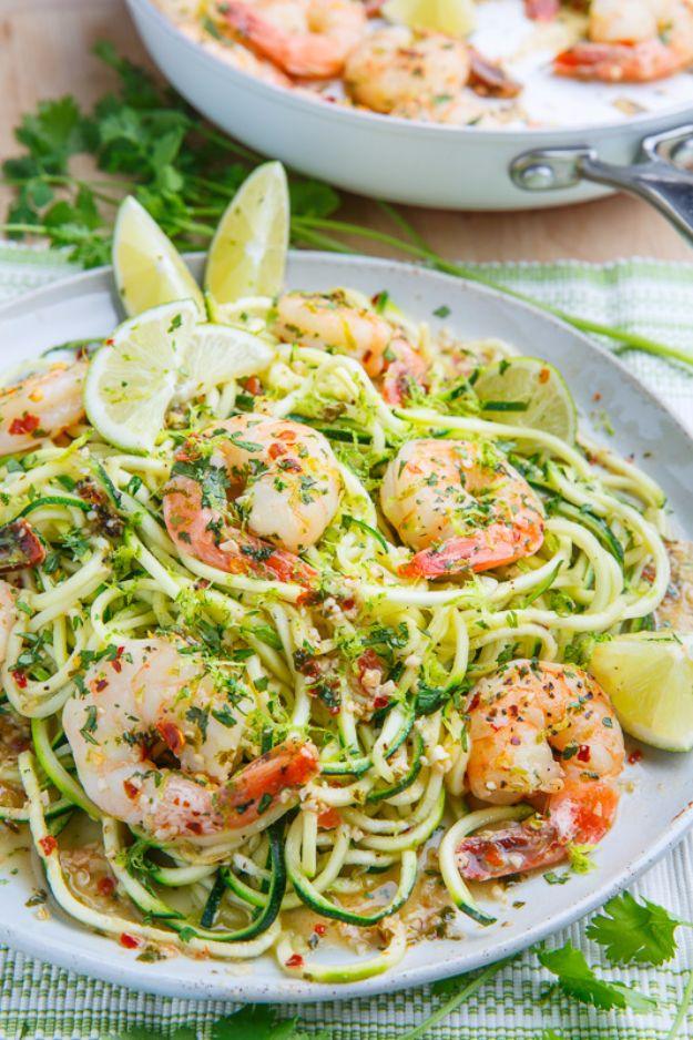 Cilantro lime shrimp scampi with pink shrimp over green zucchini noodles, lime wedges and fresh cilantro on a plate